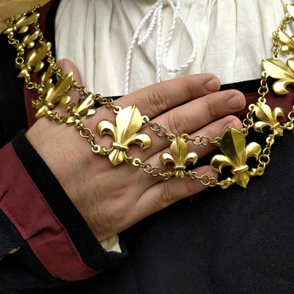 High-quality finish of the pieces on our renaissance model wearing the Brass Chain of Office, featuring a close-up view of the fleur de Lis design being held in their hands.