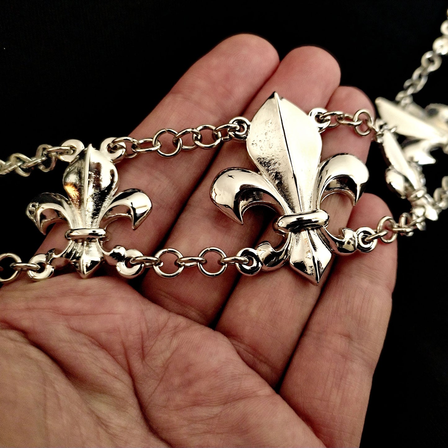 Detail of the necklace on a hand showing the size of the fleur de lis connectors of this Awesome chain of office Lis in silver finish inspired by Renaissance. Whether it's for a wedding, fair, reenactment, or theater play, this chain adds a touch of exclusivity to any occasion.