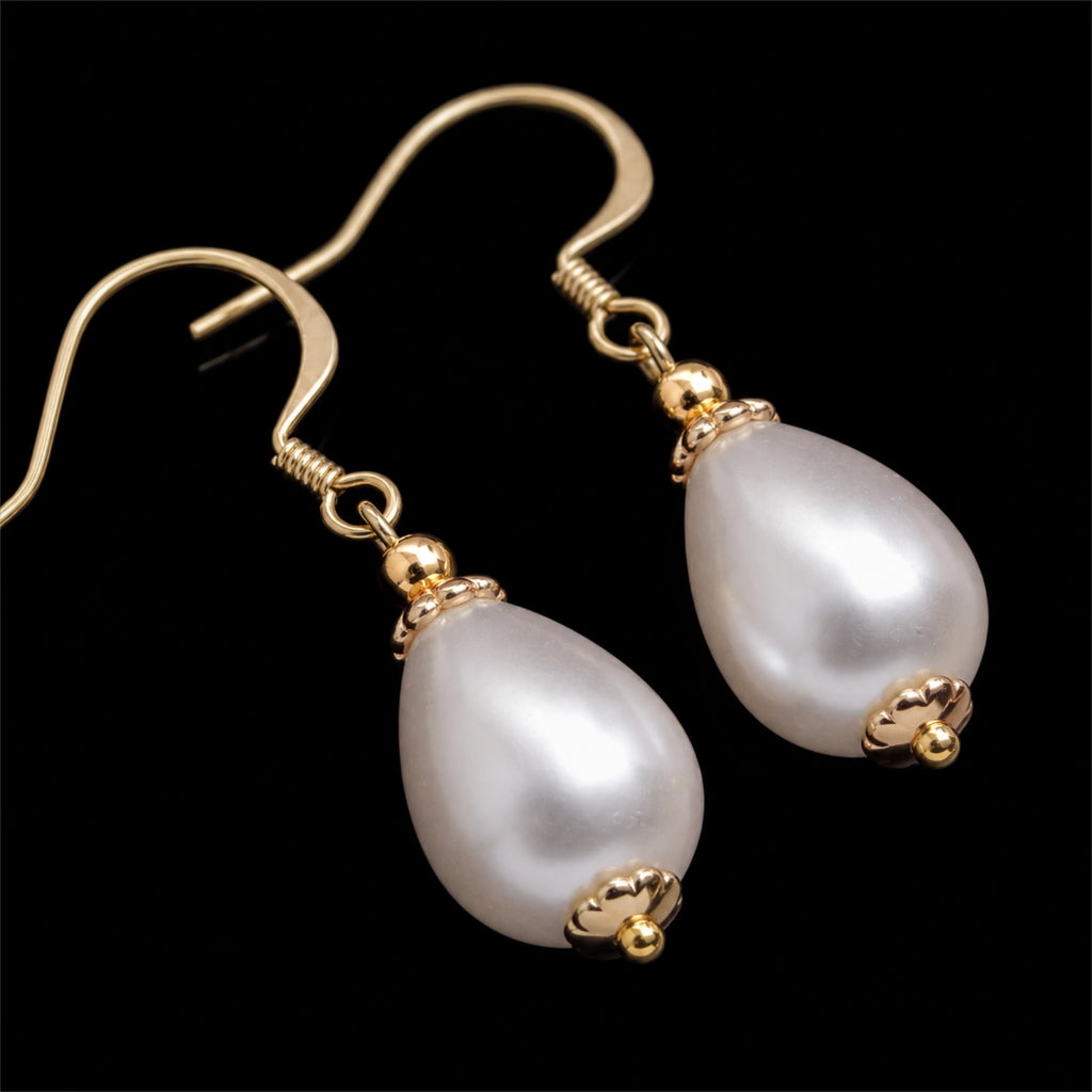 Close up daigonal image of drop pearl earrings on a pure black background