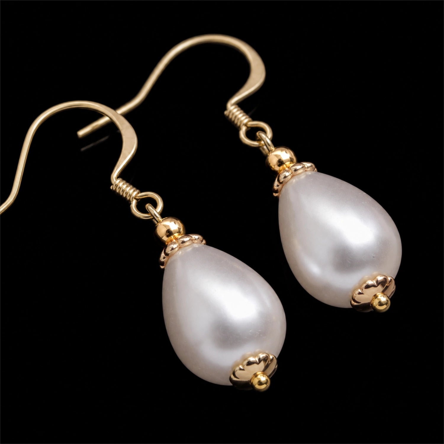 Close up daigonal image of drop pearl earrings on a pure black background