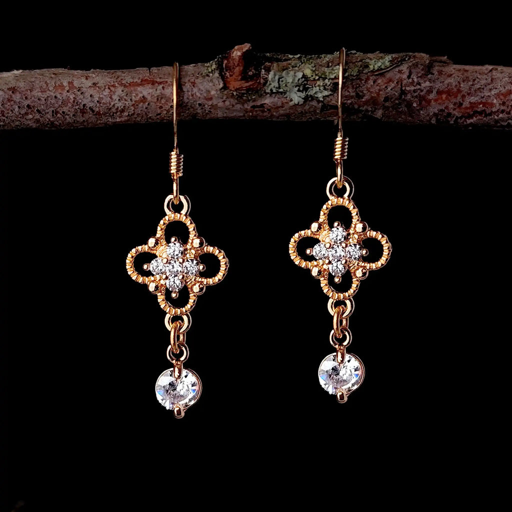 Gold Regency crystal drop earrings hanging from a branch with dark background