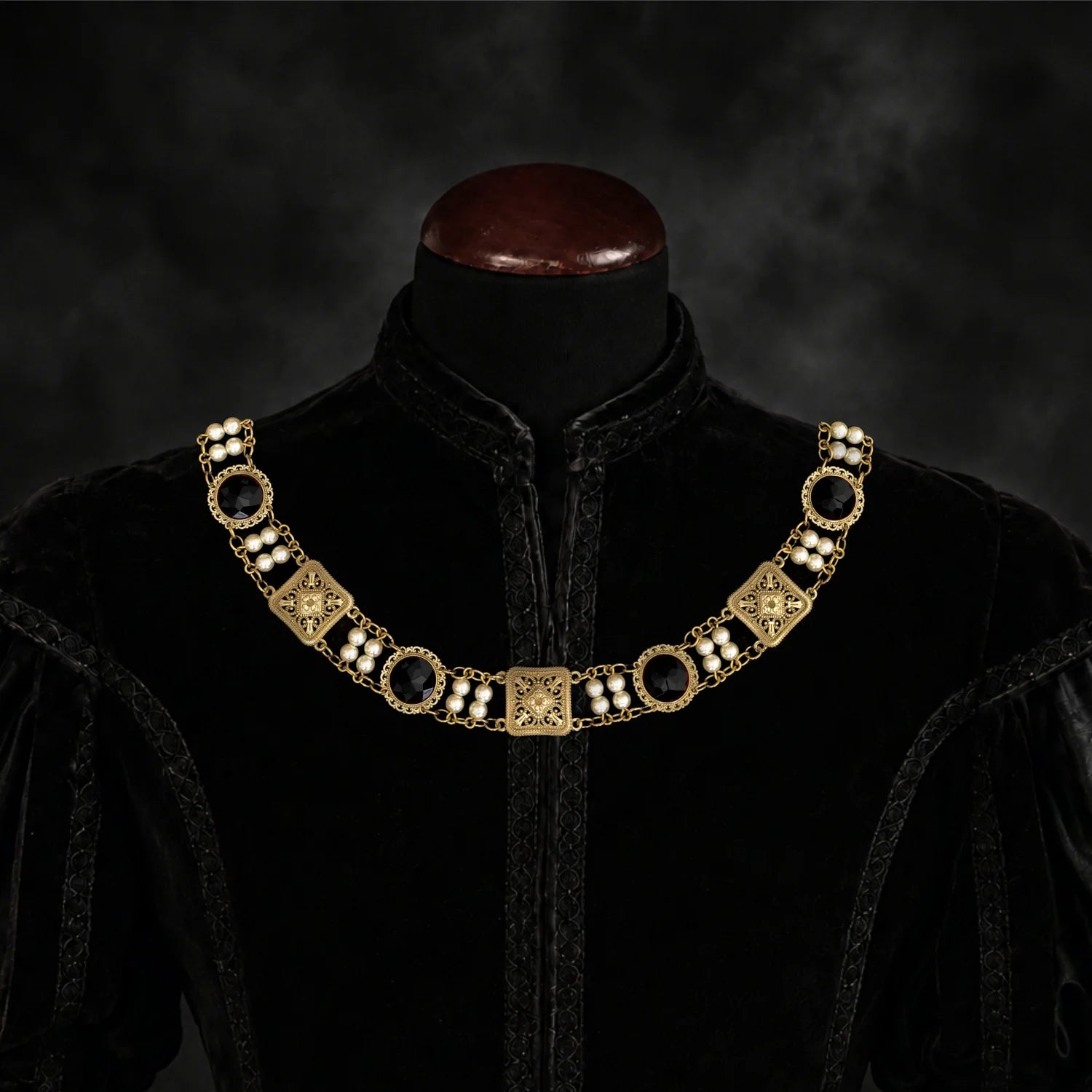 Frontal view of Ambrossio chain of foffice in brass finish with two strand of pearls and Black cabochons on a black doublet mannequin