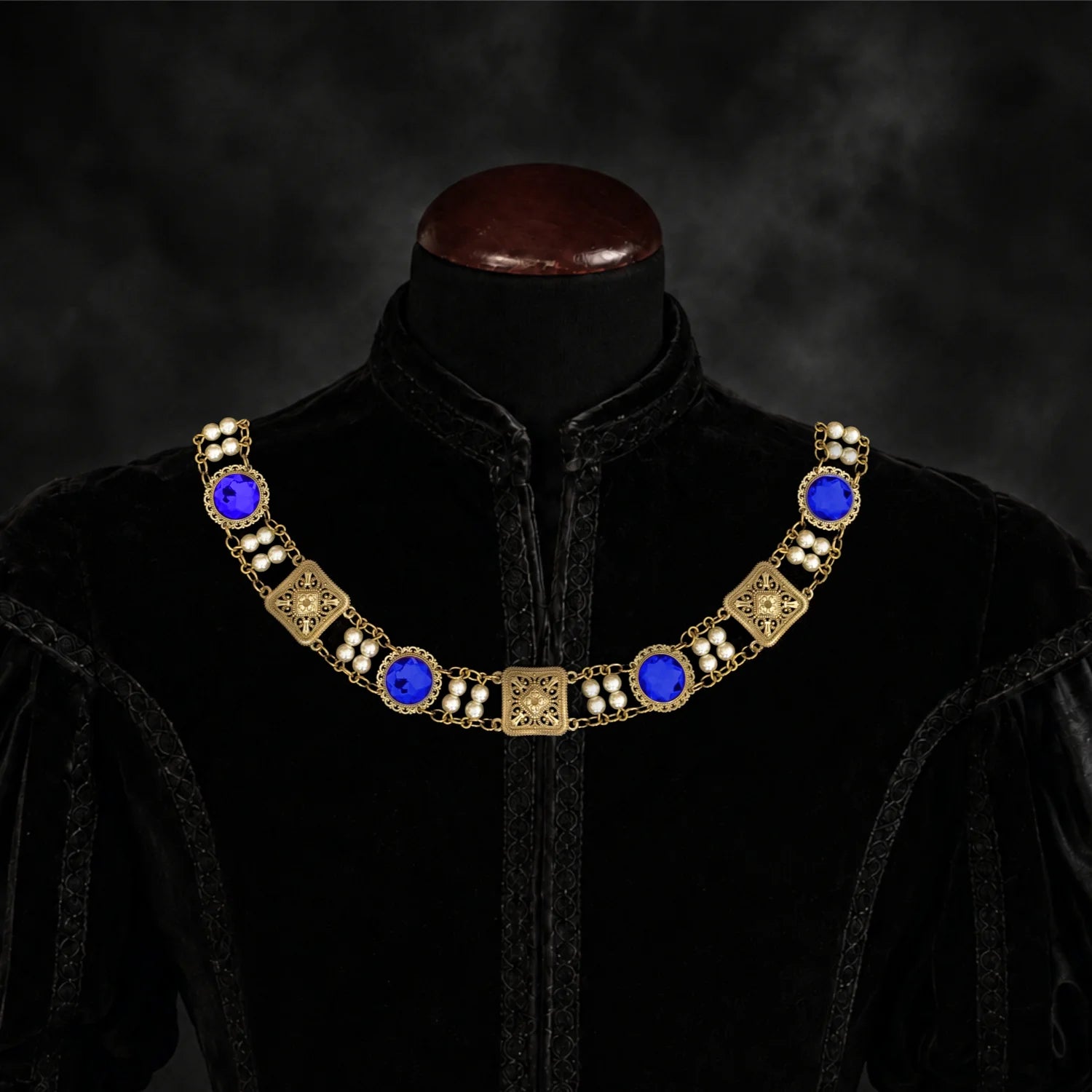 Frontal view of Ambrossio chain of foffice in brass finish with two strand of pearls and Blue cabochons on a black doublet mannequin