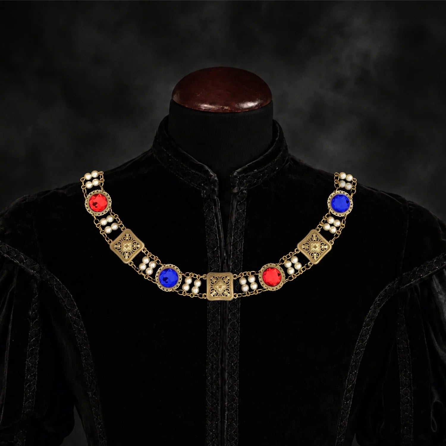 Frontal view of Ambrossio chain of foffice in brass finish with two strand of pearls and Red and blue cabochons on a black doublet mannequin