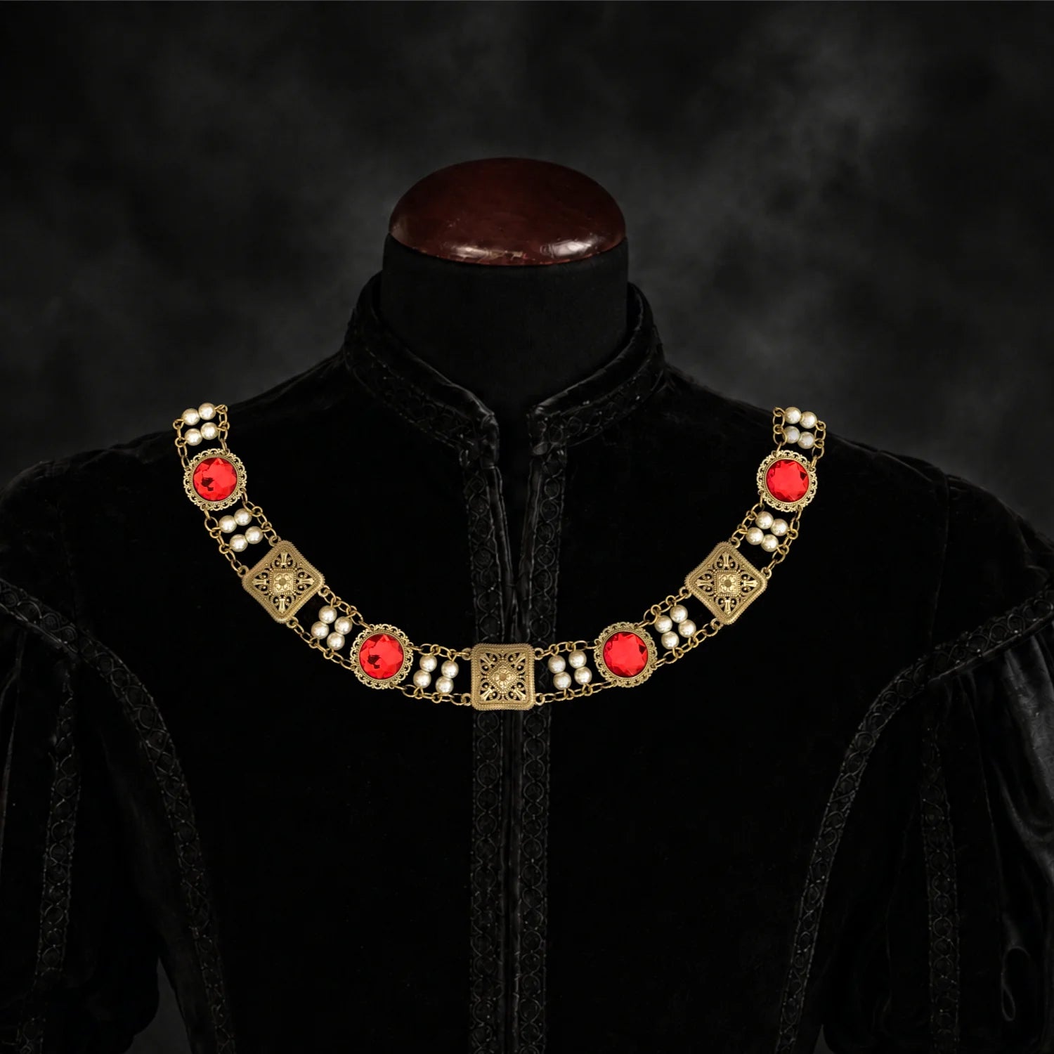 Frontal view of Ambrossio chain of foffice in brass finish with two strand of pearls and Red cabochons on a black doublet mannequin