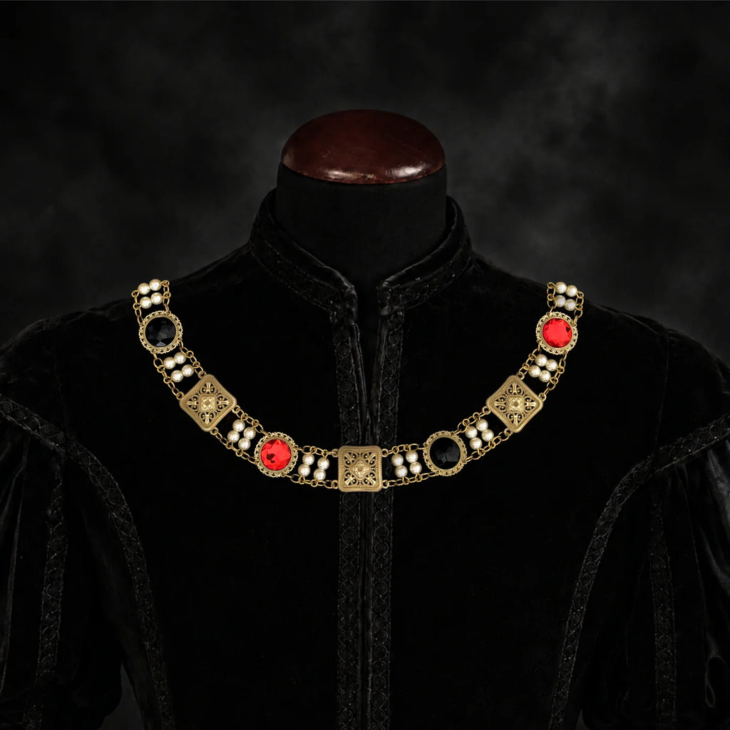 Frontal view of Ambrossio chain of foffice in brass finish with two strand of pearls between connectors and settings with Red and Black cabochons on a black doublet mannequin