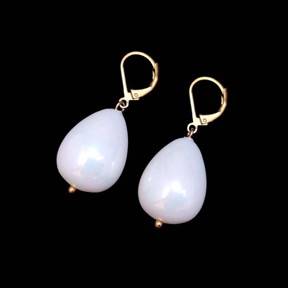 Pair of medium drop pearl Vermeer earrings on a black background.