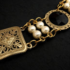 Perpective close up view of the connections of pearls and settings and connectors of Ambrossio chain of foffice in brass finish