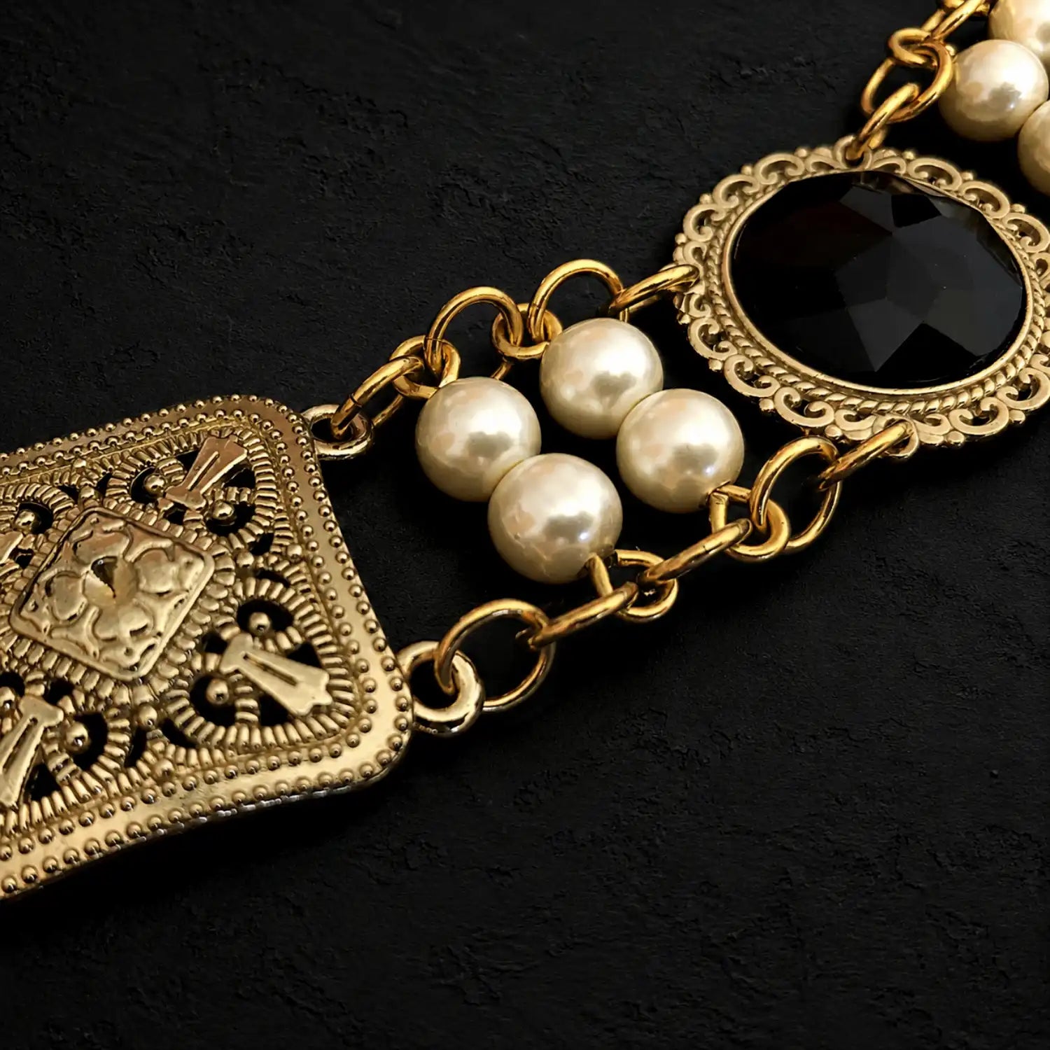 Perpective close up view of the connections of pearls and settings and connectors of Ambrossio chain of foffice in brass finish