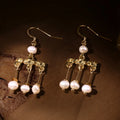 Flavia Roman crotalia replica earrings with freshwater pearls on wooden background