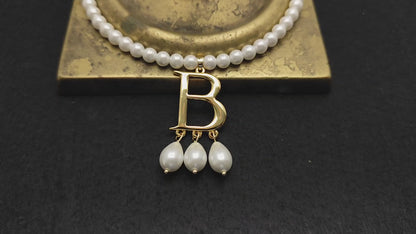 Close-up video of Anne Boleyn's necklace showing the letter B with the three medium-sized pearl pendants resting on the base of a brass candlestick.